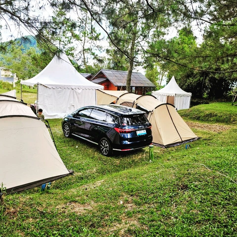Tenda dan mobil listrik di camp ground berumput